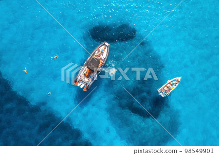 Aerial view of yachts and swimming people in blue sea at sunset 98549901