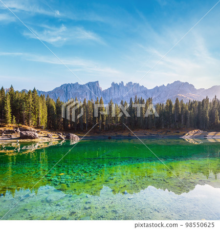 Sunny colorful autumn alpine Dolomites mountain scene, Sudtirol, Italy. Karersee or Lago di Carezza view. 98550625