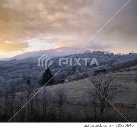 Winter coming. Last good weather days in autumn mountains countryside morning peaceful picturesque scene. Dirty road from hills to the village. 98550640