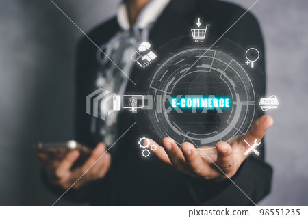 E-commerce, online shopping and retail, electronic shops, internet of things concept, Person hand holding e-commerce icon on virtual screen. E-commerce, online shopping and retail, electronic shops, internet of things concept, Person hand holding e-commerce icon on virtual screen. 98551235