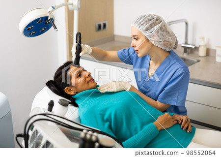 Beautician doing needle-free mesotherapy for hispanic woman Beautician doing needle-free mesotherapy for hispanic woman 98552064