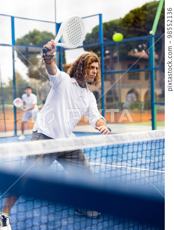 Focused adult man playing paddle tennis outdoors Focused adult man playing paddle tennis outdoors 98552136