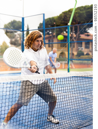 Sporty resolved man playing padel on open court 98552193
