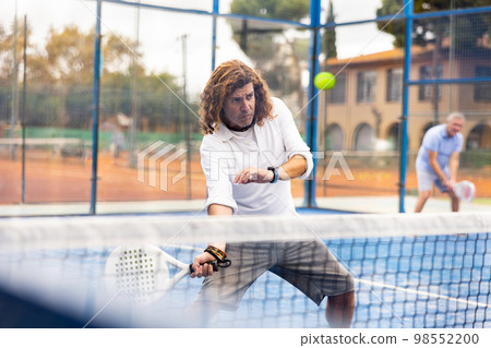 Focused adult man playing paddle tennis outdoors Focused adult man playing paddle tennis outdoors 98552200
