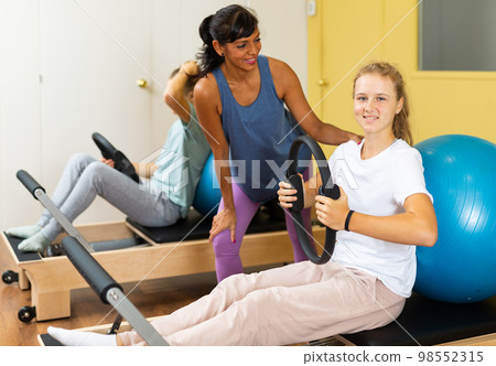 Young boy and girl with pilates trainer in gym Young boy and girl with pilates trainer in gym 98552315