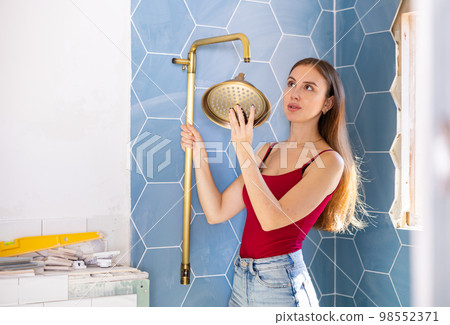Beautiful woman chooses place to install new shower during renovation work in bathroom 98552371