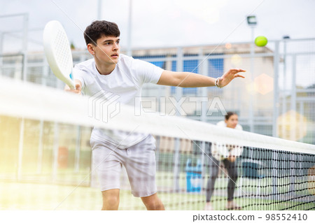 View through tennis net of an young playing padel View through tennis net of an young playing padel 98552410