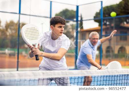 Male player ready to hits the ball while playing padel on hard court Male player ready to hits the ball while playing padel on hard court 98552477