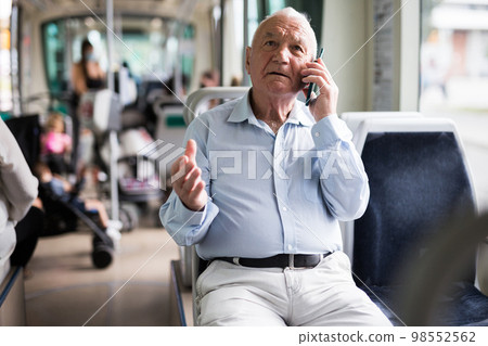 Old man in streetcar talking on phone Old man in streetcar talking on phone 98552562