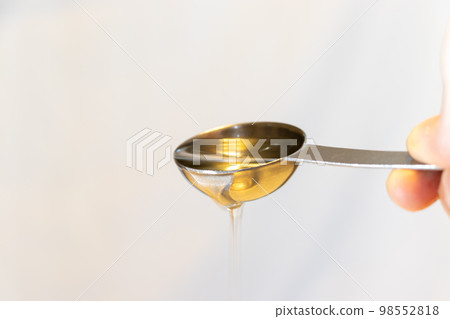 Oil dripping from a metal spoon 98552818