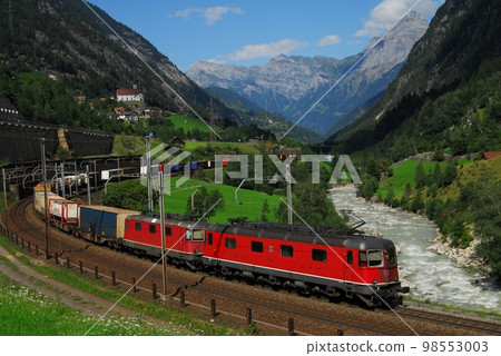 A train of the Swiss Federal Railways crossing the Gotthard Pass with the church of Wassen in the background 98553003