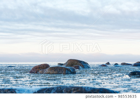 Panoramic view of the snow-covered shore of the Baltic sea at sunset. Ice fragments at sea close-up. 98553635