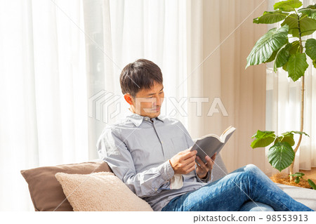 man reading a book in the living room 98553913