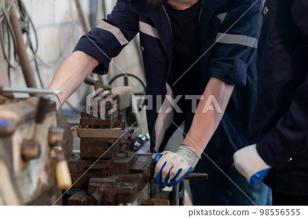 Young caucasian engineer man operating lathe machine for preparing production at factory. 98556555