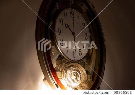 Wall clock in a dark room illuminated by lights 98556598