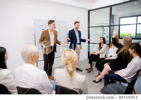 Young caucasian businessman asking opinion and brainstorm of employee while raise hand up. 98556953