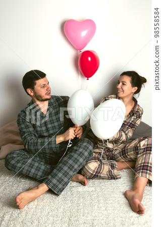 Couple of lovers holds balloons in the shape of a heart. The concept of Valentine's Day. Front view. Couple of lovers holds balloons in the shape of a heart. The concept of Valentine's Day. Front view. 98558584