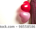 Inflatable helium balloons in the shape of a heart for Valentine's Day are held by a woman. Front view. 98558586
