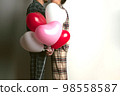 Couple of lovers holds balloons in the shape of a heart. The concept of Valentine's Day. Front view. 98558587