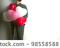 Inflatable helium balloons in the shape of a heart for Valentine's Day are held by a man. Front view. 98558588