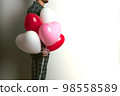 Inflatable helium balloons in the shape of a heart for Valentine's Day are held by a man. Front view. 98558589
