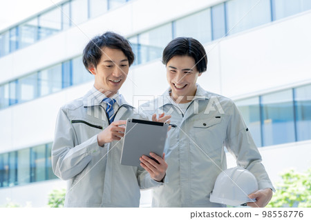 A young worker looking at a tablet in front of a building and a foreman.Photography cooperation "LINK FOREST" A young worker looking at a tablet in front of a building and a foreman.Photography cooperation "LINK FOREST" 98558776
