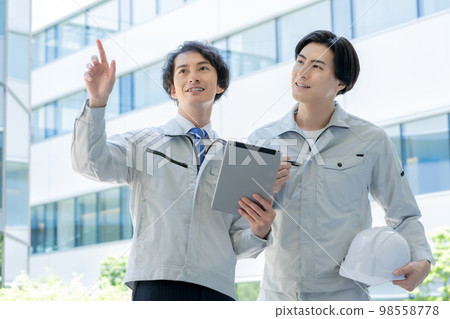 A young worker and a foreman having a meeting in front of the building.Photography cooperation "LINK FOREST" A young worker and a foreman having a meeting in front of the building.Photography cooperation "LINK FOREST" 98558778