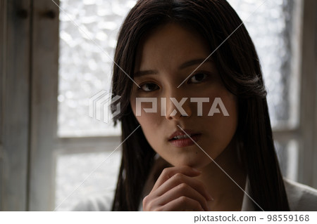 Young woman by the window Young woman by the window 98559168