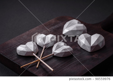 Beautiful tasty sweet candies in gray color on a dark concrete background Beautiful tasty sweet candies in gray color on a dark concrete background 98559976
