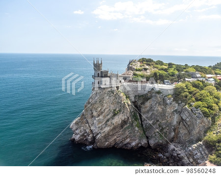 Crimea Swallow's Nest Castle on the rock over the Black Sea. It is a tourist attraction of Crimea. Amazing aerial view of the Crimea coast with the castle above abyss on sunny day. 98560248