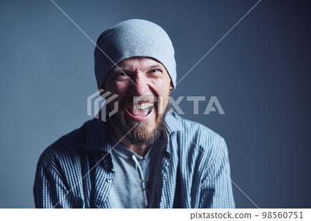 Mature 30s man in beanie hat crazy laughing at camera 98560751