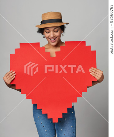 Mixed race african american caucasian girl in straw hat holding big paper pixel style heart shape with copy space for text Mixed race african american caucasian girl in straw hat holding big paper pixel style heart shape with copy space for text 98560765