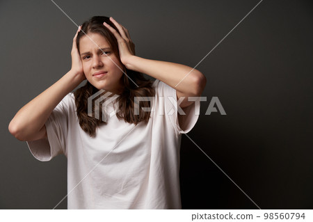 Worried girl with sullen eyebrows holding her head in hands 98560794