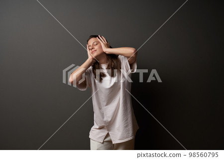 Casual girl with closed eyes holding her head in hands 98560795