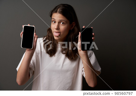 Woman showing blank screens of two smart phones holding in hands 98560797