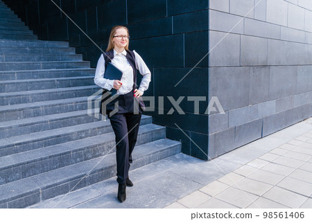 Business caucasian woman holding a laptop and outdoors surrounded by buildings. Business caucasian woman holding a laptop and outdoors surrounded by buildings. 98561406