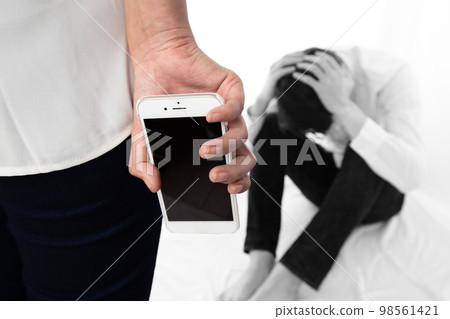 A man holding his head to a woman with a smartphone A man holding his head to a woman with a smartphone 98561421