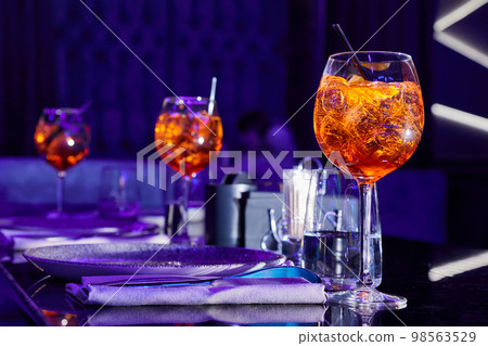 Alcoholic cocktails with ice and a pieces of orange on the served table of the nightclub Alcoholic cocktails with ice and a pieces of orange on the served table of the nightclub 98563529