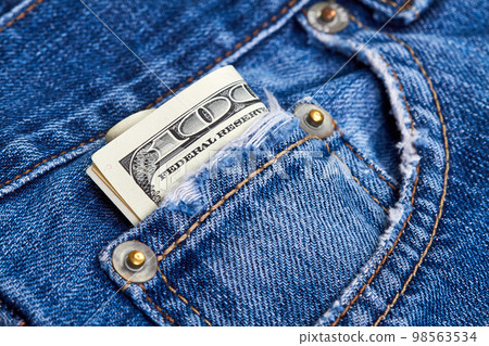 Rolled up one hundred dollar bills in jeans pocket Rolled up one hundred dollar bills in jeans pocket 98563534