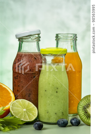 Green, orange and red smoothie in glass bottles. Green, orange and red smoothie in glass bottles. 98563995