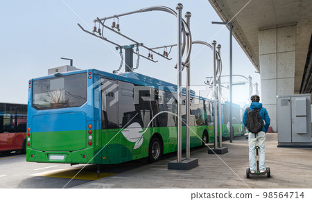 Man on electric scooter next to electric bus Man on electric scooter next to electric bus 98564714