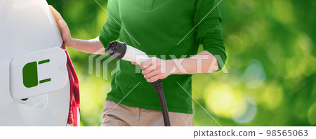 A man stands by an electric car A man stands by an electric car 98565063