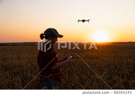 Farmer controls drone with a tablet on a sunset. 98565243