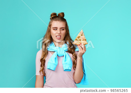 young woman looks with disgust at slice of pizza 98565265