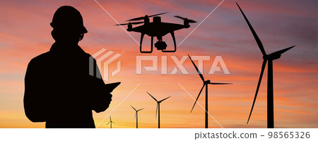 Silhouette of engineer with tablet computer, drone and wind turbines 98565326