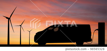 Silhouette of electric van with charging station and wind turbines 98565328