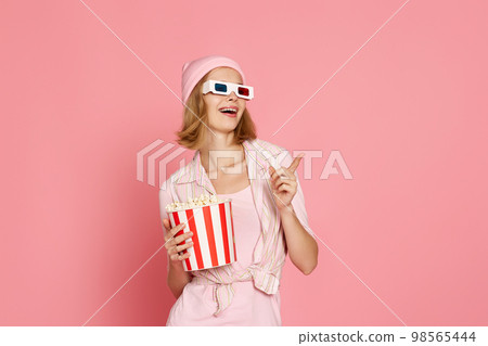 woman in t-shirt and hat with popcorn pointing at the copy space 98565444