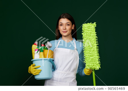 woman in cleaner apron holding bucket of detergents and mop 98565469