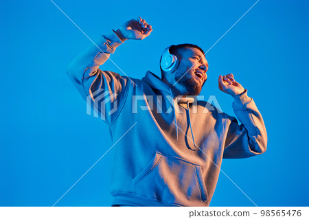 man with headphones in sweatshirt enjoying favorite music man with headphones in sweatshirt enjoying favorite music 98565476