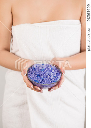 A woman in a towel is holding a purple bath salt 98565699